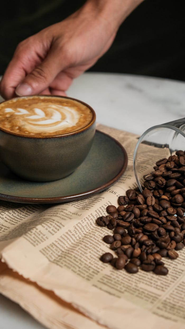 Handcrafted coffee with latte art, surrounded by coffee beans on a rustic table.